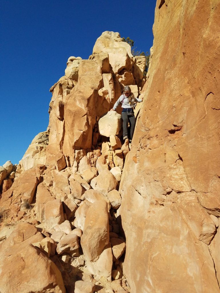 Kristy scrambling down a steep rock face, to represent navigating our own mindset  